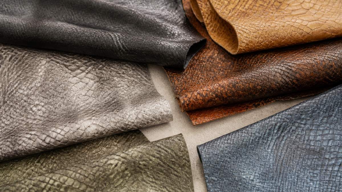 Close-up of finished fish leather pieces showing natural texture variation, subtle scale patterns, and rich color depth arranged on neutral surface with soft natural lighting
