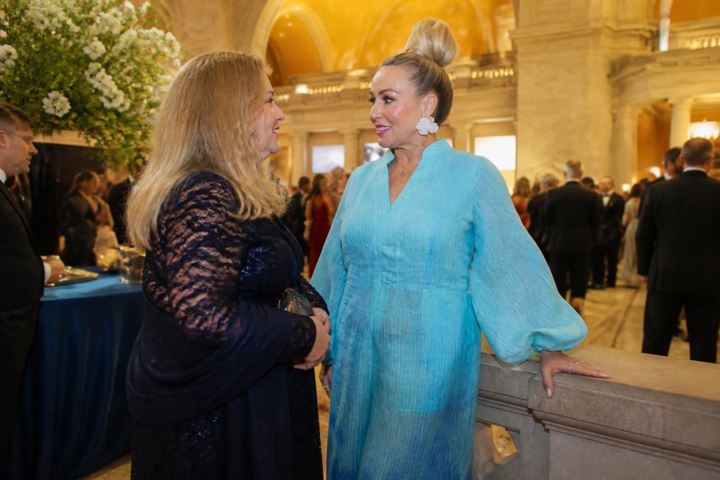 Woman in a blue ombré organza jumpsuit with balloon sleeves at a formal gala, demonstrating the flowing silhouette and gradient effect of the fabric