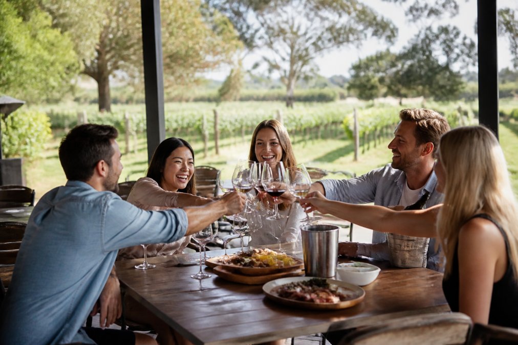 Infographic showing a full-day Swan Valley wine tour itinerary featuring friends toasting at a vineyard cellar door.