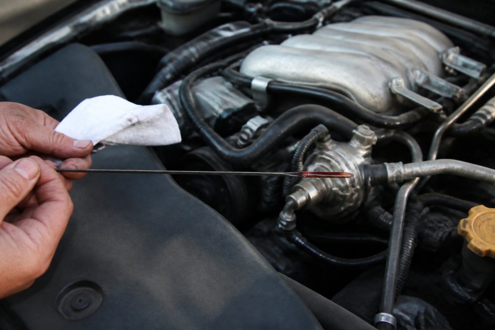 Mechanic checking a transmission dipstick for signs of an overfilled transmission with a rag nearby