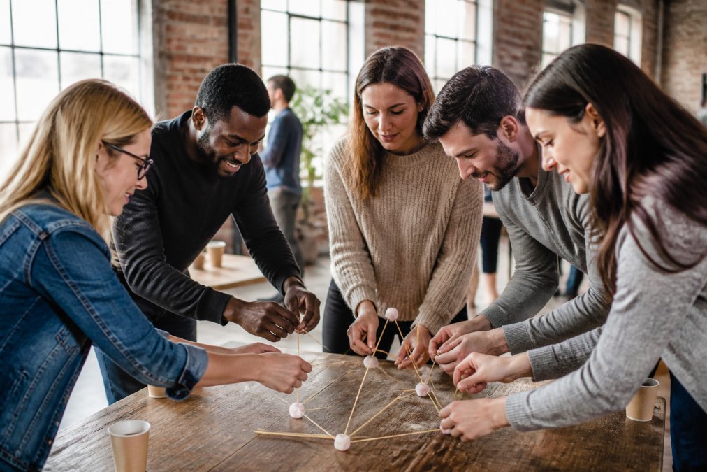 Team members collaborating on a hands-on activity together, working toward a shared goal with focus and cooperation, natural lighting in modern workspace