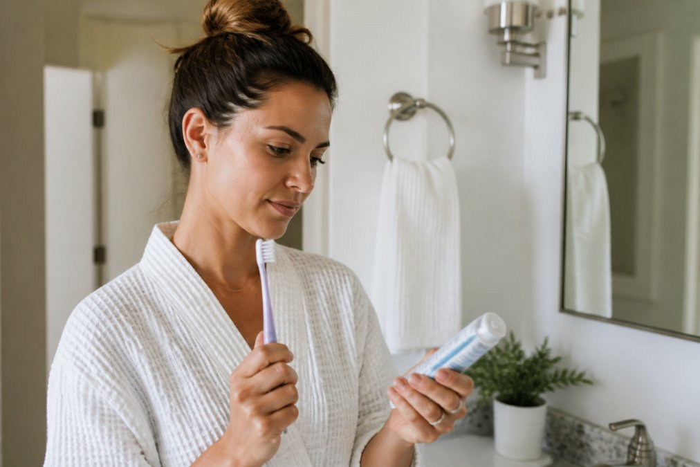 Person holding desensitizing toothpaste while preparing for teeth whitening at home