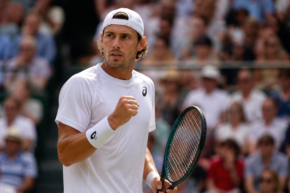 Focused competitive tennis player on court during intense match moment, displaying concentrated expression and composed body language during a tiebreak situation with crowd visible in background