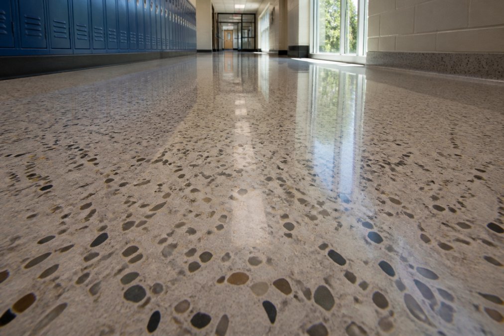 Close-up of a terrazzo floor surface showing the decorative aggregate pattern and polished finish in a school corridor with natural light highlighting the surface clarity