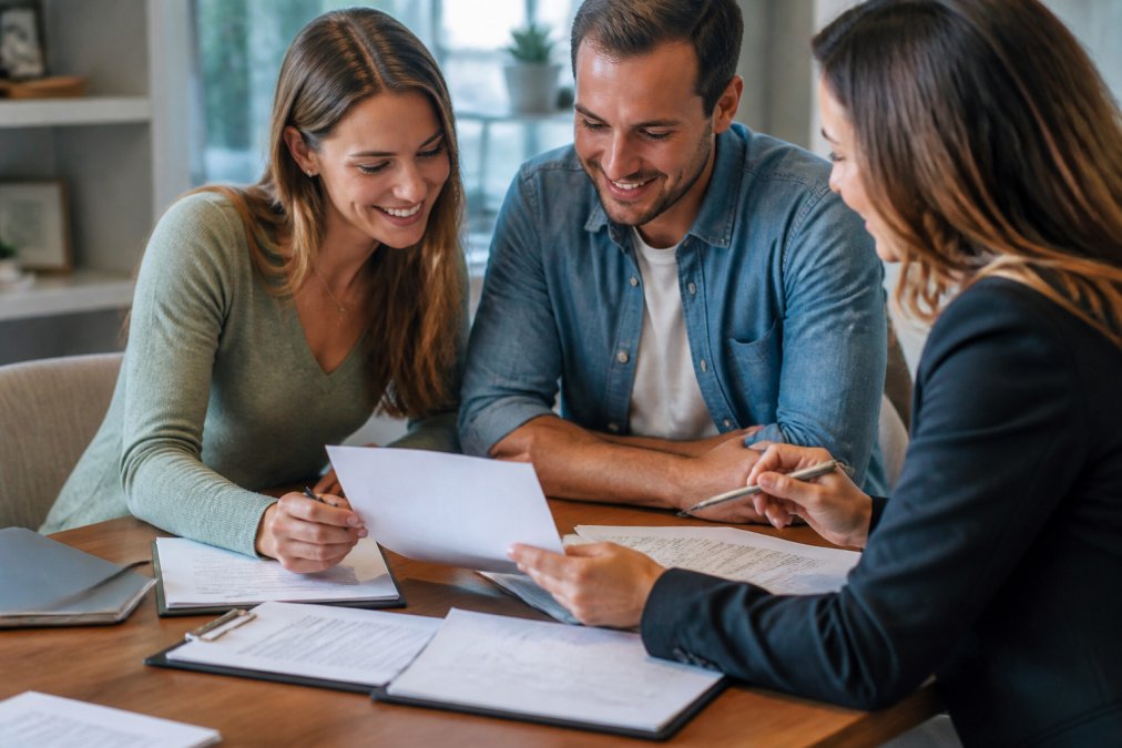 First-time homebuyer reviewing loan estimate paperwork and closing cost tips with their real estate team at a desk.