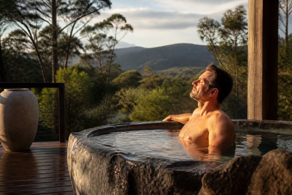Business leader in a luxury retreat sanctuary in natural Tasmanian setting, transitioning from tense posture to calm, grounded presence with peaceful surroundings