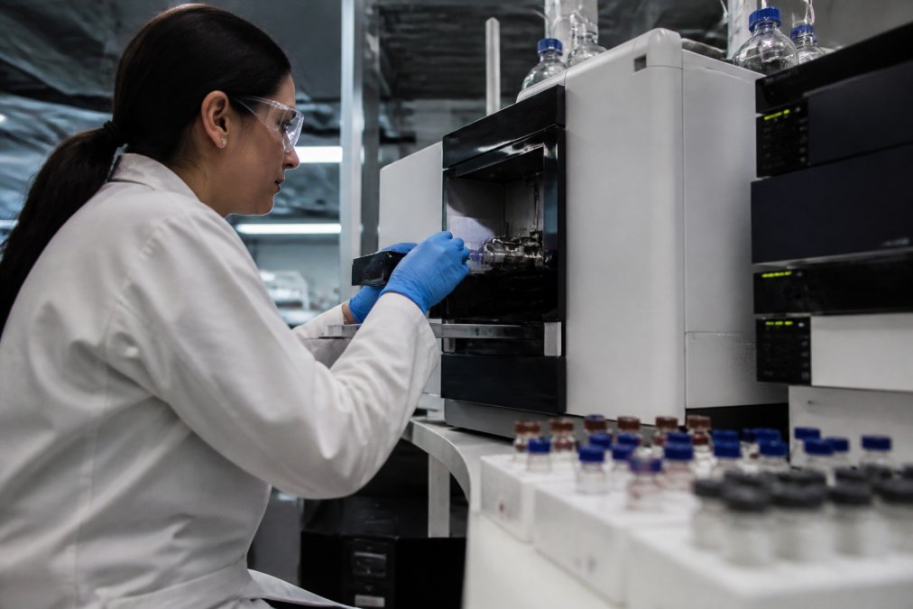 Laboratory technician in white coat analyzing samples with analytical instruments in modern accredited testing facility