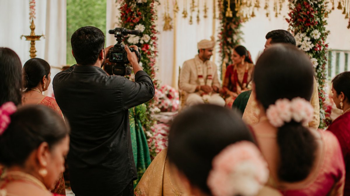 Videographer filming a colorful ceremony for Asian wedding videography from a discreet side angle