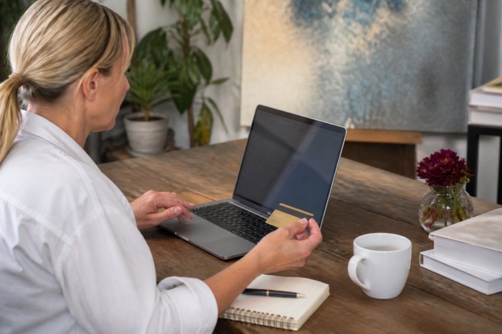 Person at a desk completing a secure online art purchase on a laptop, with secure checkout page and payment gateway interface visible on screen, natural office lighting