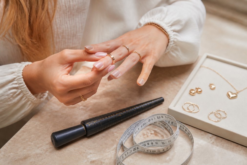 Persoon die een ring voorzichtig op een vinger past terwijl ze een meetlint of ringmaatstok naast zich heeft liggen