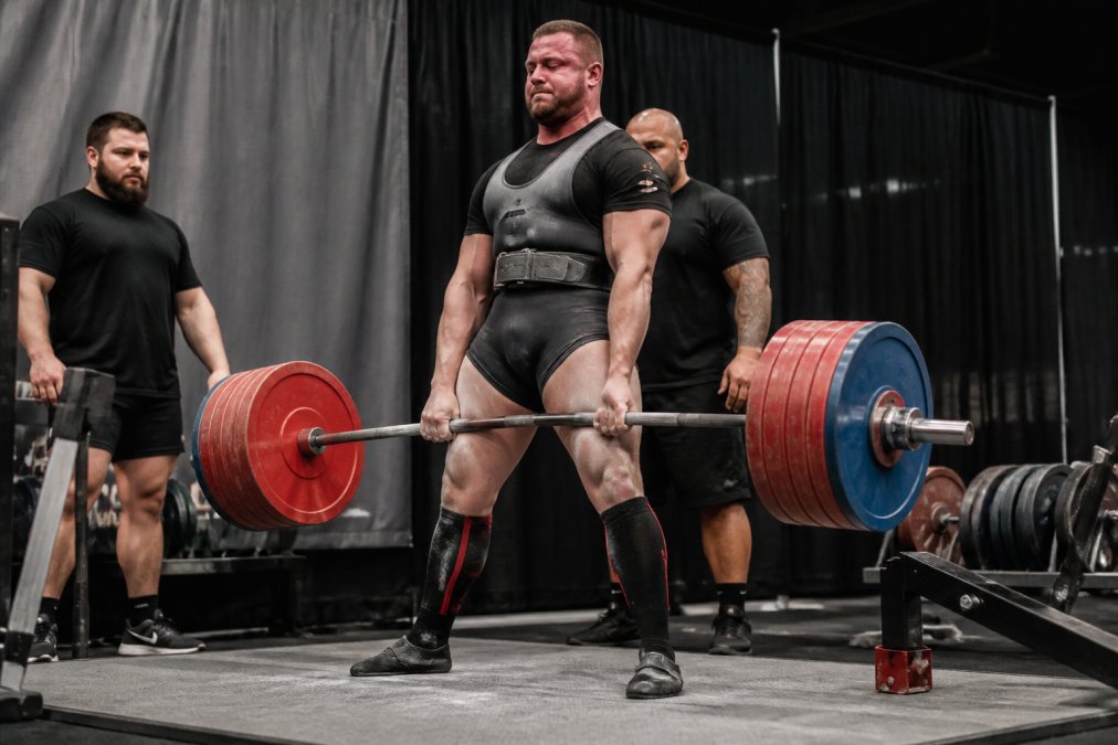 Athlete performing a heavy deadlift wearing a lever belt, demonstrating lumbar support and core stability engagement during the lift at a powerlifting competition