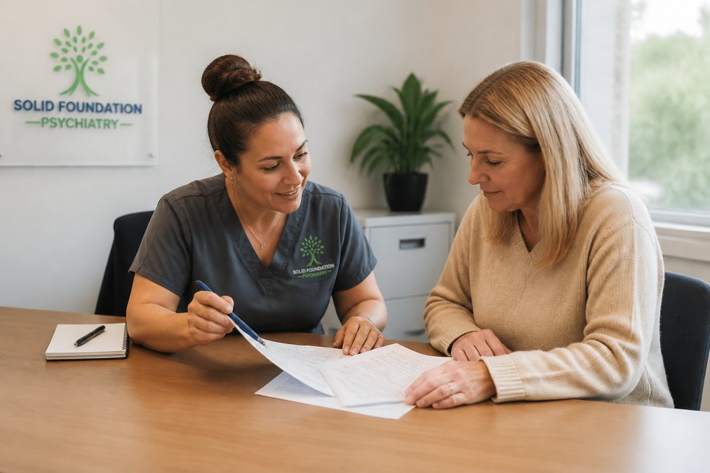 A compassionate mental health professional sitting with a patient in a bright, welcoming office, reviewing insurance paperwork together at a desk with a laptop and notes visible