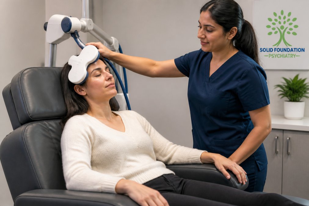 Patient seated in a comfortable clinical chair during a TMS session with a trained technician nearby, showing the magnetic coil positioned against the patient's head in a calm, professional medical setting with soft lighting