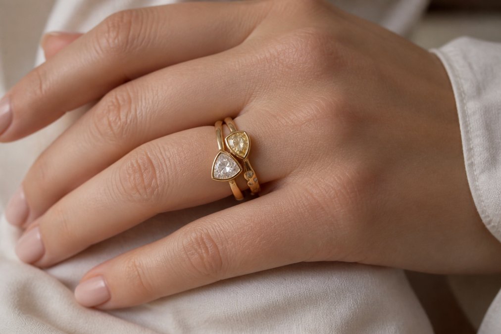 Close-up of a hand wearing a toi et moi engagement ring stacked with a flush-fit wedding band in 18k gold, showing the seamless pairing and stone orientation with soft natural light highlighting the gemstones