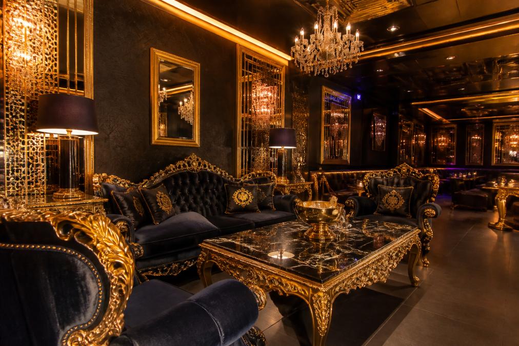 Ein eleganter VIP-Lounge-Bereich in einem exklusiven Club mit barocken Möbeln, goldenen Akzenten und warmem, indirektem Licht