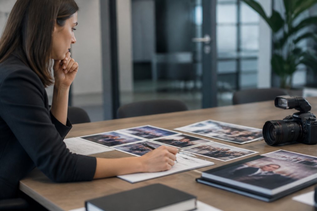 Marketing manager reviewing event photography analytics on a laptop screen, with a detailed engagement dashboard displaying social media metrics, website traffic, and conversion data in the background