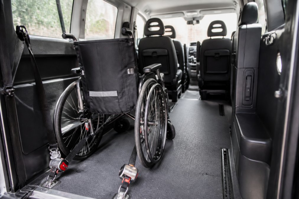 Interieur van een moderne rolstoeltaxi met zichtbare veiligheidsuitrusting, bevestigingssystemen voor rolstoelen, en voldoende ruimte voor passagiers met mobiliteitsbeperking