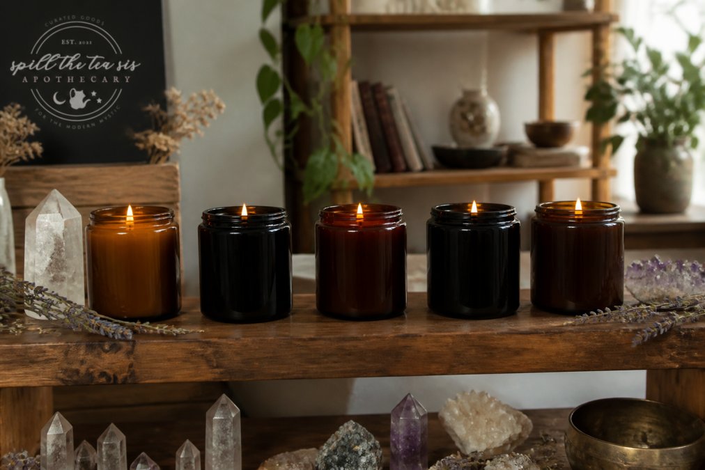Five lit sustainable intention candles in glass jars arranged with crystals and dried herbs on a cozy shelf.