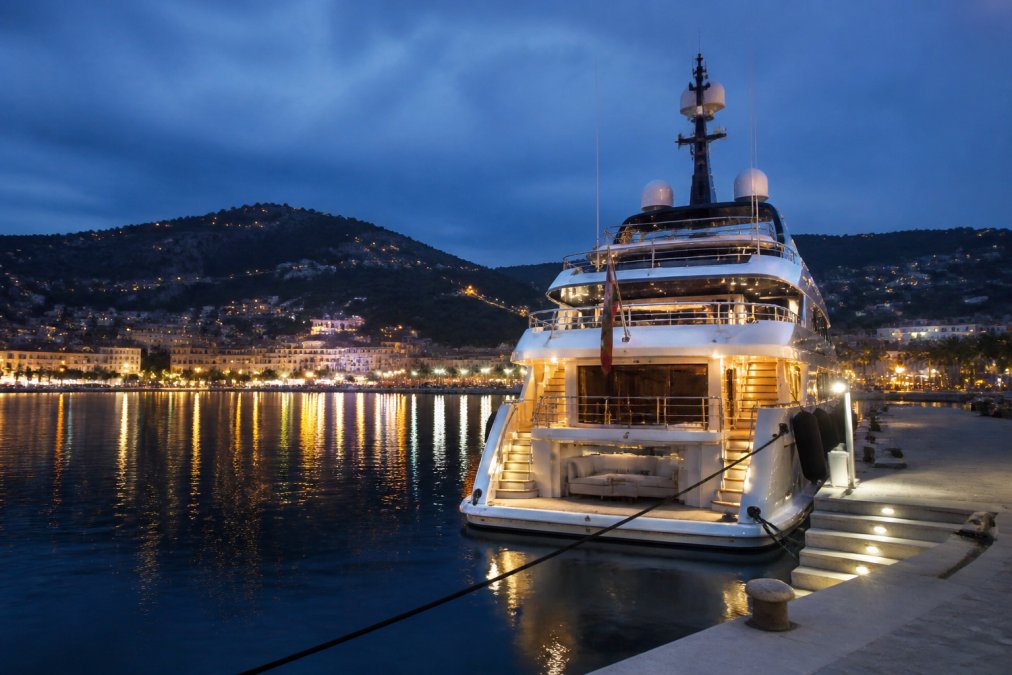 A luxury superyacht moored in a French Riviera harbour at dusk, perfect for a Mediterranean yacht charter.