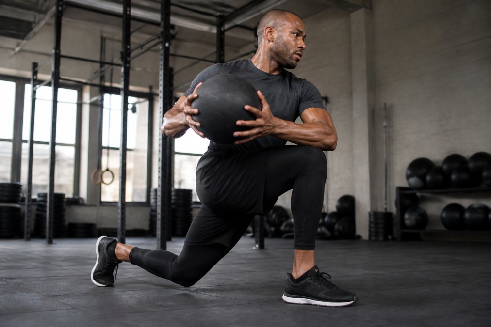 Athlete wearing premium athletic gear performing intense functional fitness movement in modern gym with natural lighting, demonstrating breathability and range of motion during cross-training workout