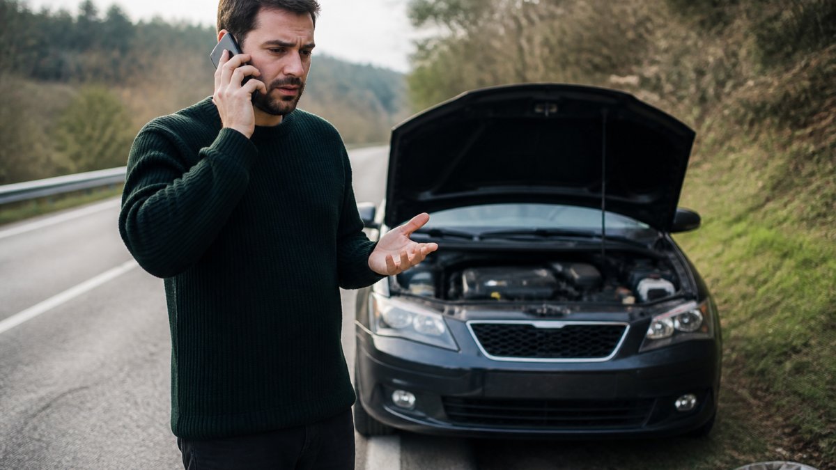 Driver on the roadside calling for help to verify their towing insurance coverage after a vehicle breakdown
