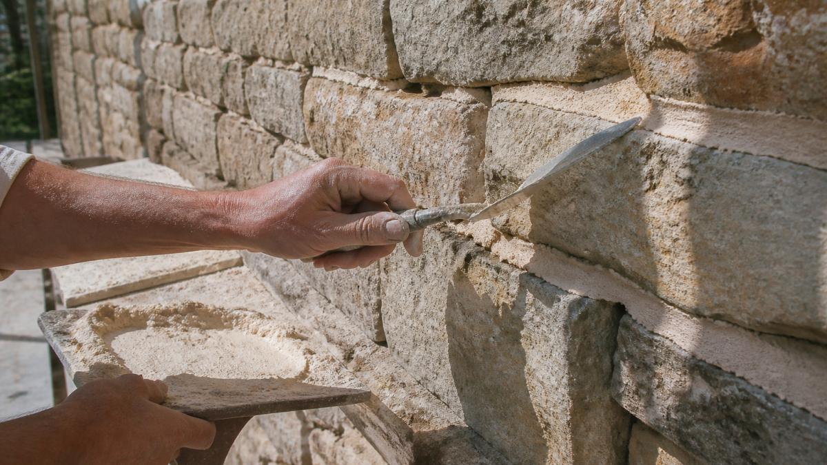 Step-by-step process of applying lime mortar using traditional building techniques on stone masonry joints.