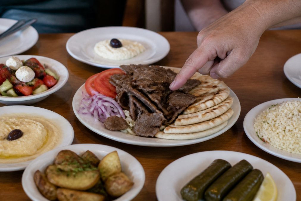 Infographic guide illustrating healthy greek food portion sizes for a family-style meal and gyro servings.