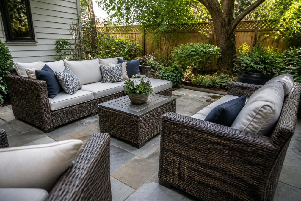 Well-arranged outdoor seating area with weather-resistant wicker furniture and thick cushions on a small patio, showing how comfortable seating is positioned to maximize a compact space