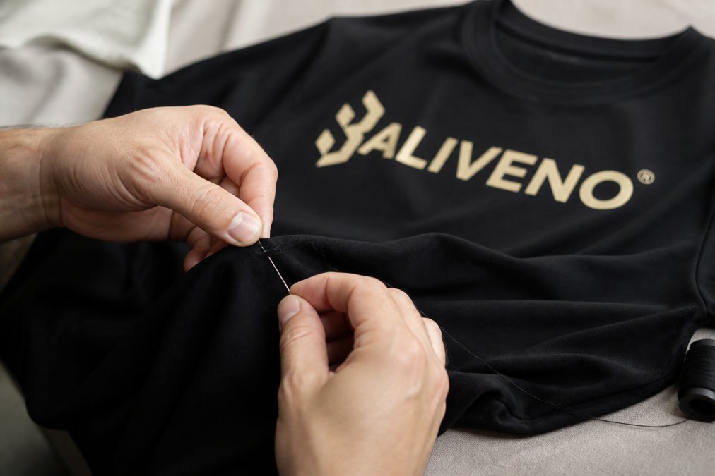 Hands carefully mending a seam or small hole in a garment using needle and thread, showing the care and attention to extending clothing lifespan, with soft focused lighting