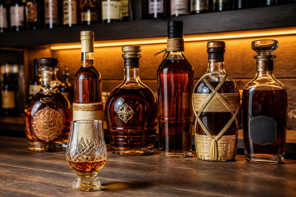 Premium rum bottles and a crystal tasting glass as a travellers liquors alternative on a wooden shelf
