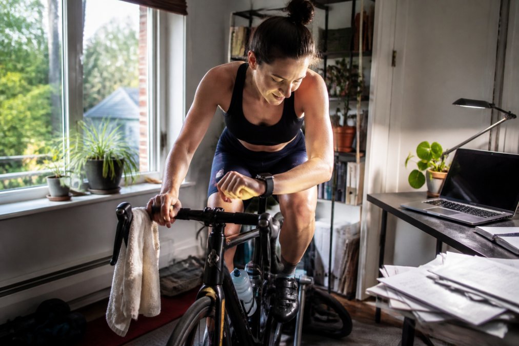 Athlete finishing an indoor bike trainer session in a home office for triathlon coaching preparation