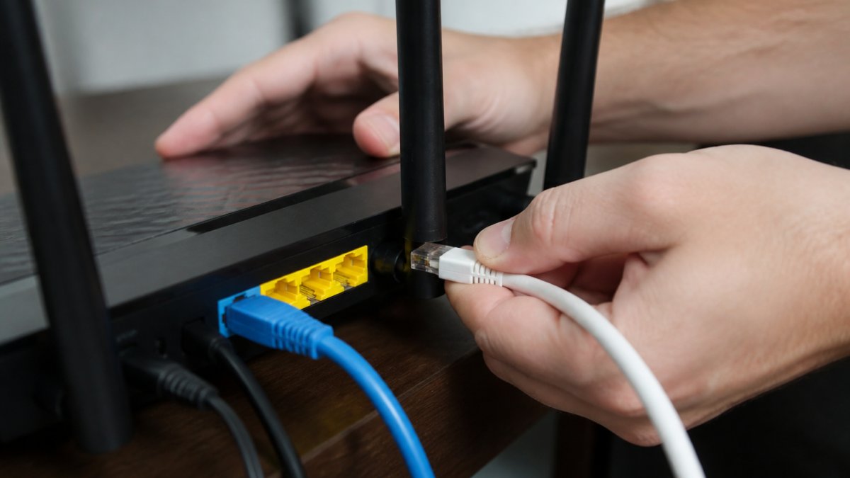 Close-up of hands checking Ethernet cable connections into router ports, showing proper cable insertion with clear view of RJ45 connectors