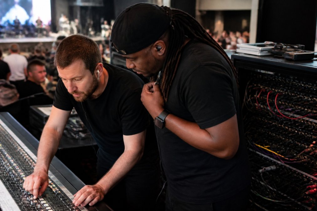 Sound technician troubleshooting stage equipment at a mixing console during a live worship service