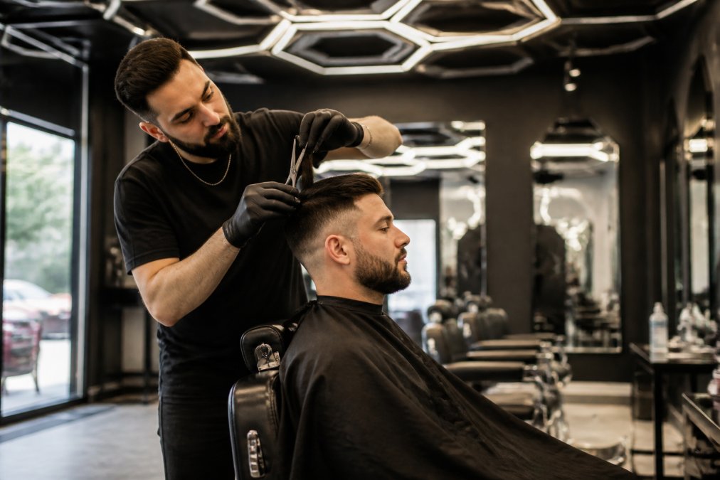 Un barbier fiable à Montréal réalise une coupe précise aux ciseaux dans un salon moderne à l'éclairage élégant.