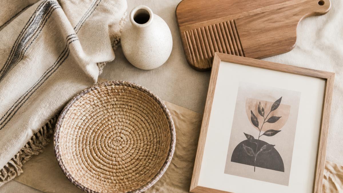 Flat-lay of a curated home decor collection featuring a ceramic vase, woven basket, linen throw, and wood board.