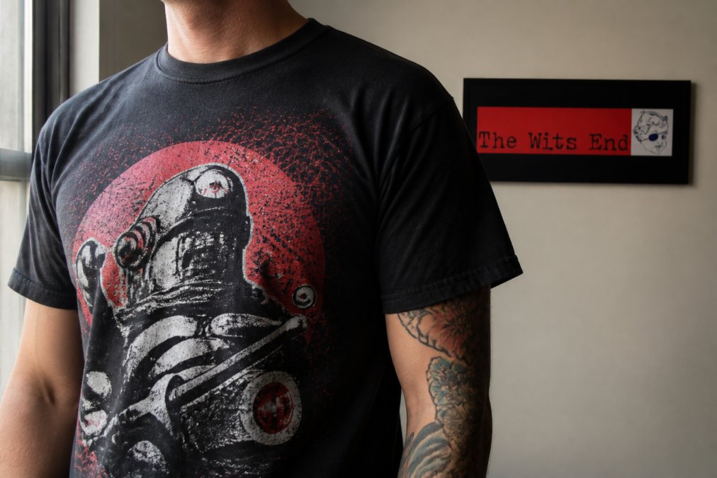Close-up of a bold graphic design clothing t-shirt showing detailed screen-printed textures in soft window light.