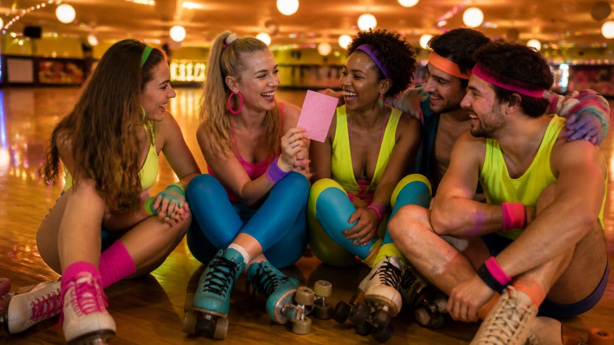 Friends in neon retro outfits laughing while roller skating at a rink with a 30th birthday invitation card