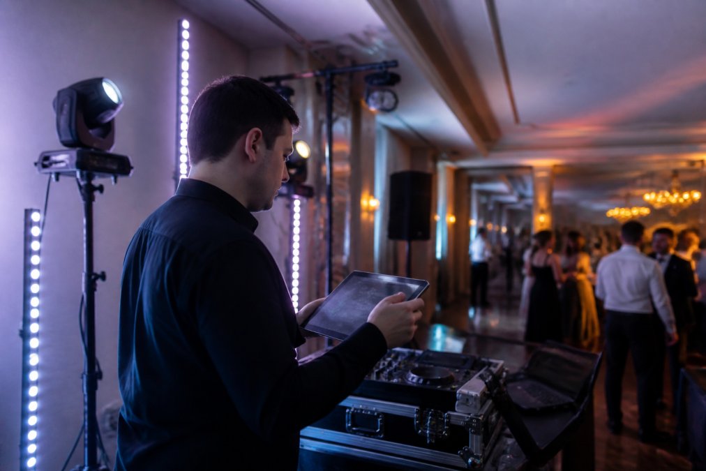 Mobile DJ at a live event with Govee smart light strips mounted on stage, checking scene controls on a tablet while managing the lighting during performance