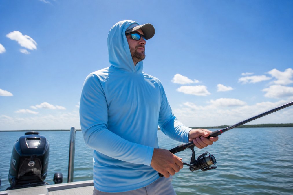 Outdoor enthusiast wearing long-sleeve UV protective fishing shirt in bright sunlight on the water, showing proper arm and torso coverage with breathable fabric