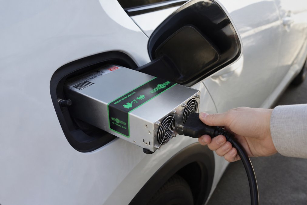 Zbliżenie adaptera typu 2 podłączonego do wtyczki V2L samochodu elektrycznego z widocznym w świetle naturalnym gniazdem Schuko, ręka podłączająca kabel