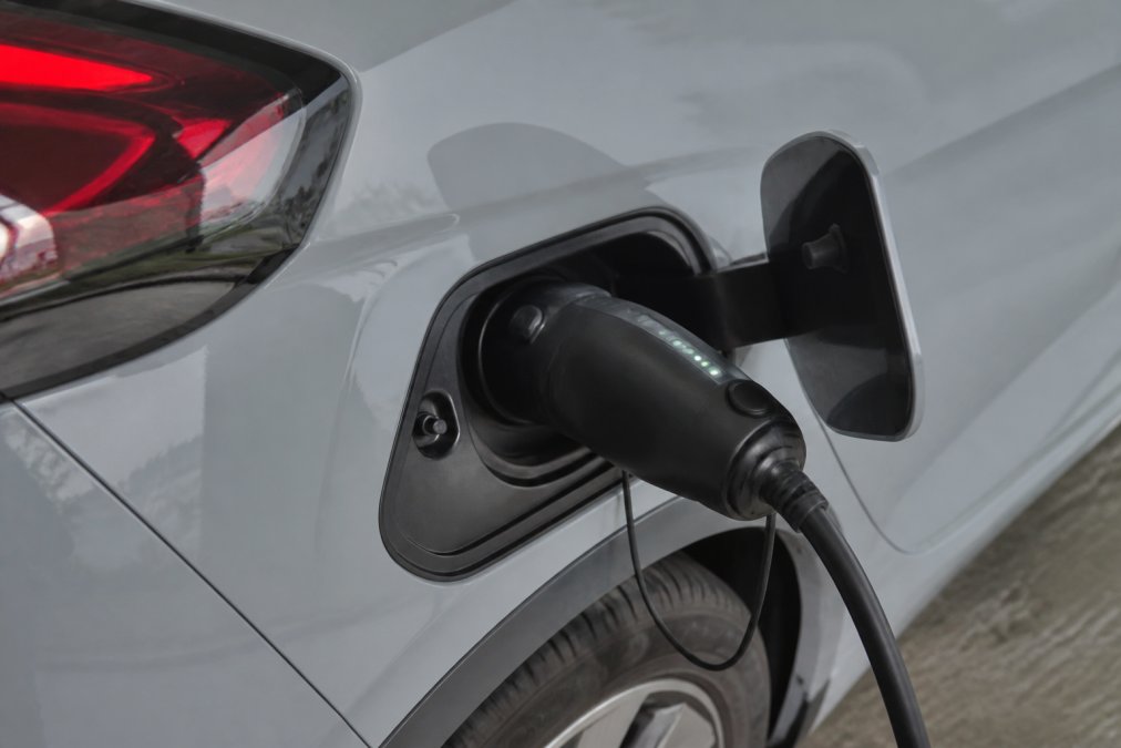 Posnetek od blizu adapterja V2L, priključenega na polnilno vtičnico za električni avtomobil, z vidnimi varnostnimi indikatorji in LED lučkami, profesionalna namestitev