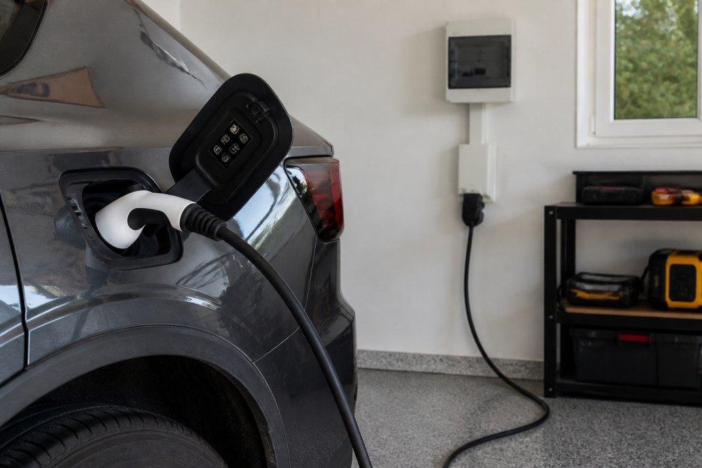 Krupni plan adaptera tipa 2 spojenog na priključak za punjenje električnog automobila s profesionalno instaliranim kablovima, utičnicom i sigurnosnom opremom u modernoj garaži