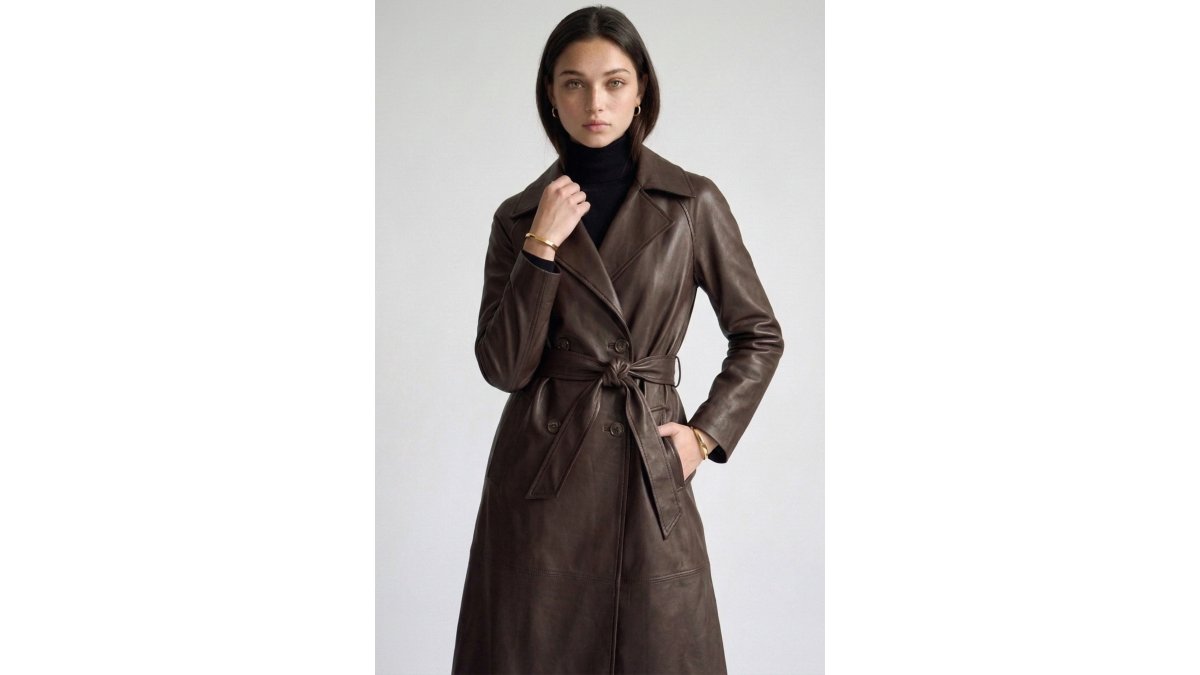 Woman styled in layered trendy pieces from a curated boutique collection, wearing a dusty blush floral corset dress with a vegan leather belted trench coat and high-rise jeans, in natural daylight in a modern home setting