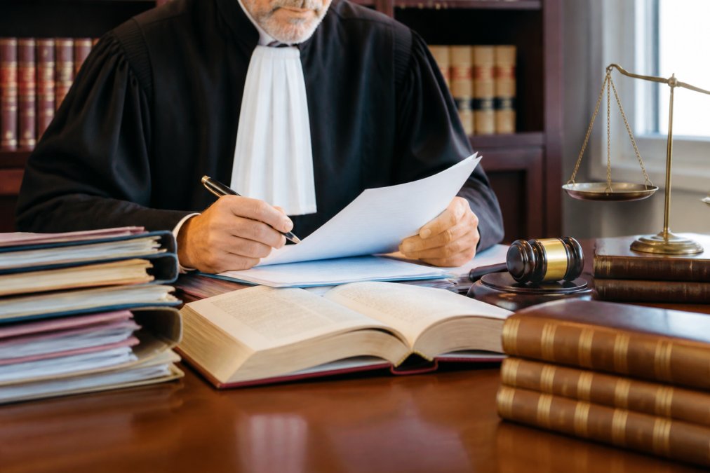 Intérieur d'un tribunal belge ou cabinet juridique avec dossiers et codes civils, professionnel du droit examinant des documents, environnement formel et structuré
