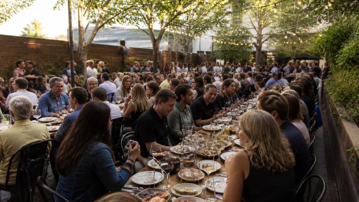 Communal tables in a Palo Alto wine garden set for 100 guests under glowing string lights at sunset