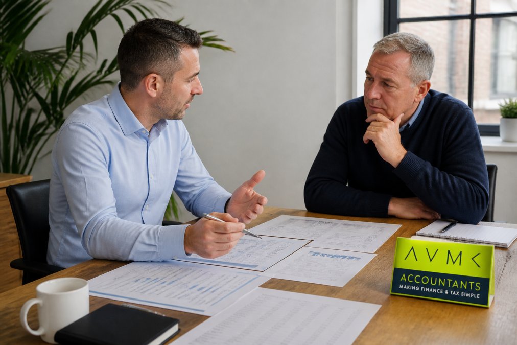 Professional finance manager discussing quarterly results with business owner at conference table with management accounts, cash flow forecasts, and business strategy documents