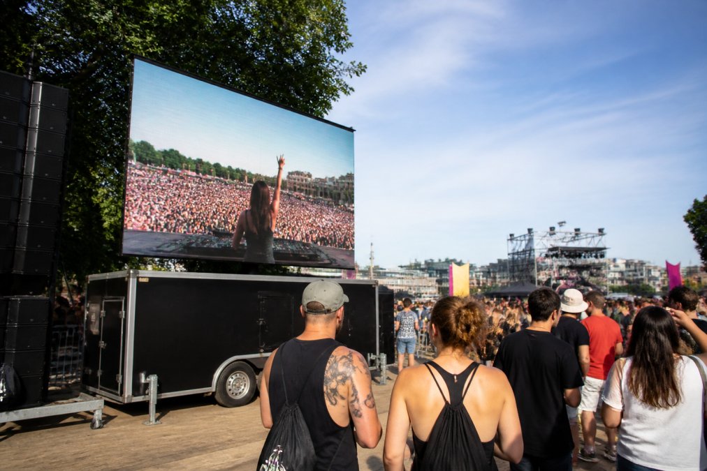 Mobiel LED-scherm op aanhangwagen op druk openluchtfestival in Antwerpen, met bezoekers die naar het heldere, kleurrijke scherm kijken in daglicht, dynamische beelden duidelijk zichtbaar ondanks zonlicht