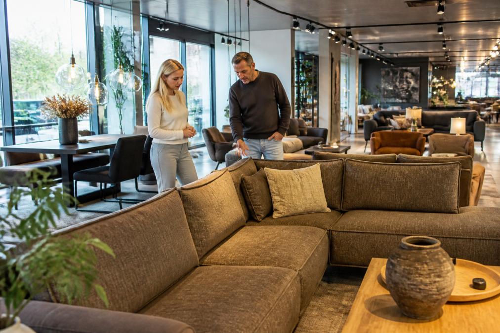 Klant in een moderne showroom van 3.000 m2, bekijkt meubels samen met een verkoper, gezellige sfeer met natuurlijk licht