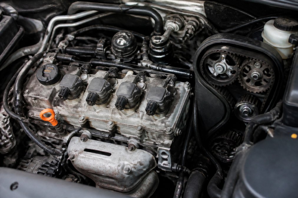 A clean, well-lit shot of a Volkswagen Jetta engine bay with the plastic engine cover removed to reveal four ignition coil packs and the timing belt cover in sharp focus
