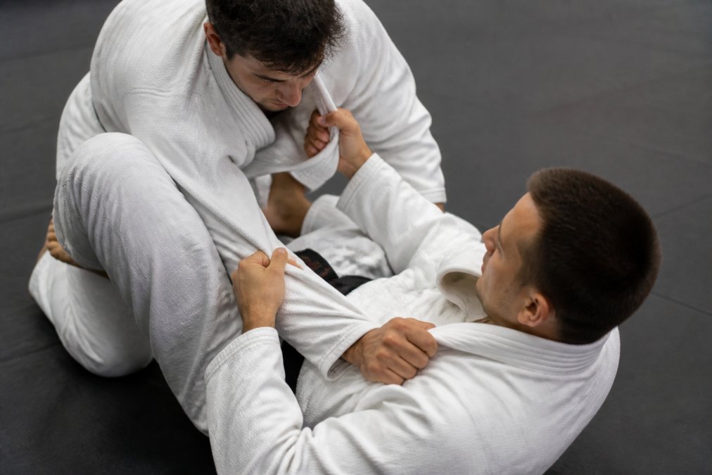 Close-up van twee BJJ-atleten in gi's die grappling oefenen op de mat, met focus op de grip op de mouwen en kraag van de kimono
